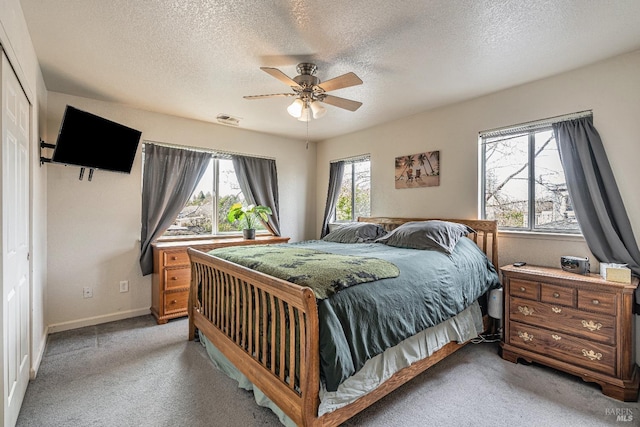 bedroom featuring light carpet, multiple windows, visible vents, and a ceiling fan