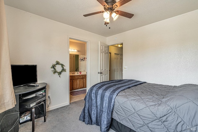 carpeted bedroom featuring a ceiling fan, ensuite bath, baseboards, and a textured ceiling