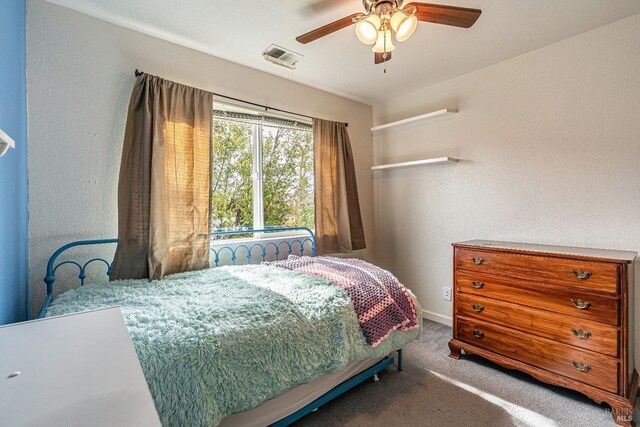 bedroom with baseboards, visible vents, a ceiling fan, a textured wall, and carpet