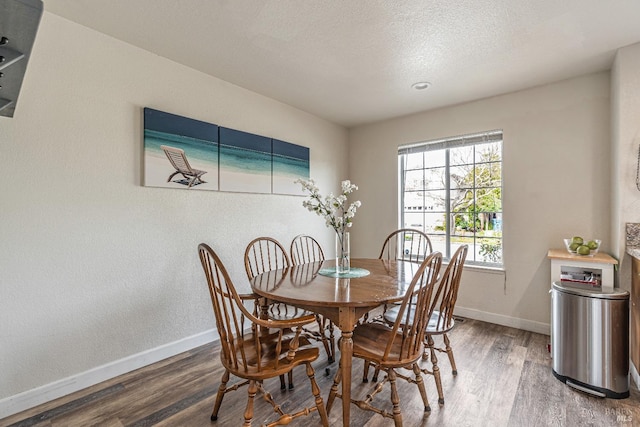 dining room with a textured ceiling, wood finished floors, and baseboards