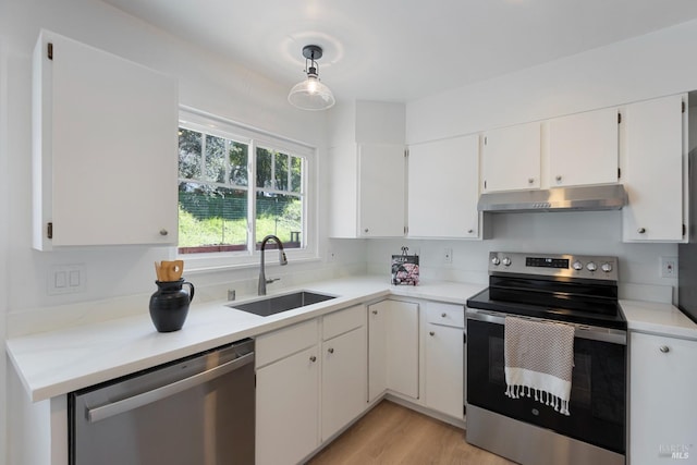 kitchen featuring white cabinets, stainless steel appliances, light countertops, under cabinet range hood, and a sink