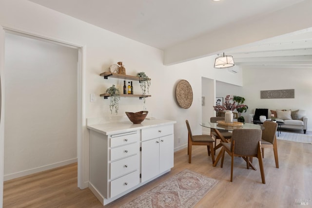 dining area with vaulted ceiling with beams, light wood-type flooring, and baseboards