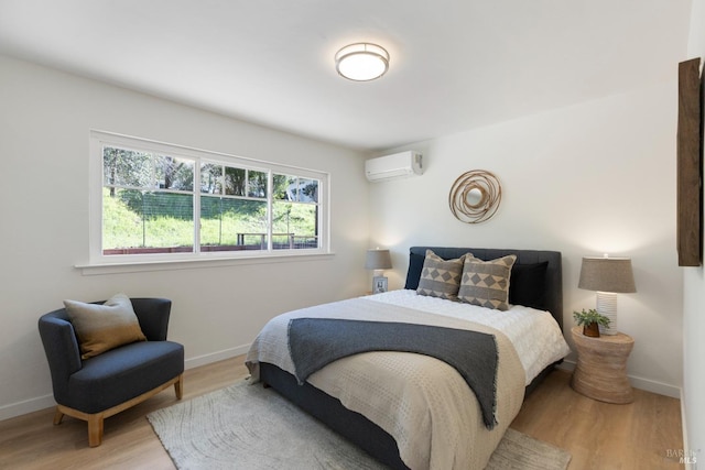 bedroom with baseboards, wood finished floors, and a wall mounted air conditioner