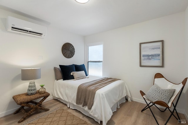 bedroom featuring an AC wall unit, wood finished floors, and baseboards