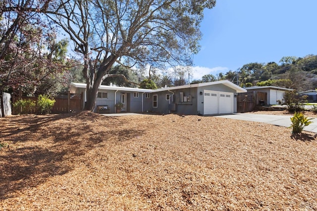 ranch-style home with an attached garage, driveway, and fence