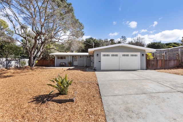 ranch-style home with concrete driveway, an attached garage, covered porch, fence, and stucco siding