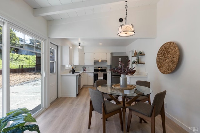 dining space with light wood-type flooring, vaulted ceiling with beams, and baseboards