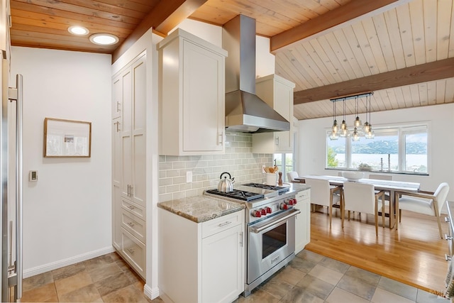 kitchen with backsplash, designer range, light stone countertops, wall chimney exhaust hood, and beamed ceiling