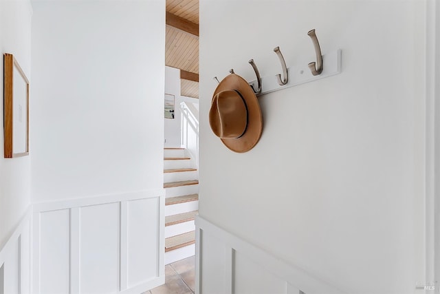 room details featuring wainscoting, wooden ceiling, beam ceiling, and a decorative wall