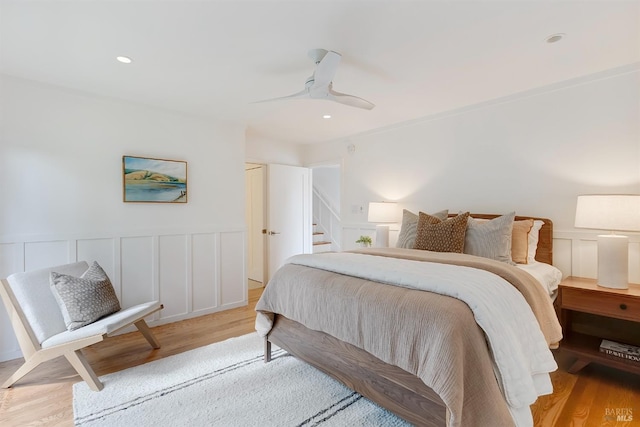 bedroom featuring recessed lighting, light wood-type flooring, a ceiling fan, and a decorative wall