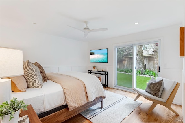 bedroom featuring light wood-type flooring, access to outside, ceiling fan, and wainscoting