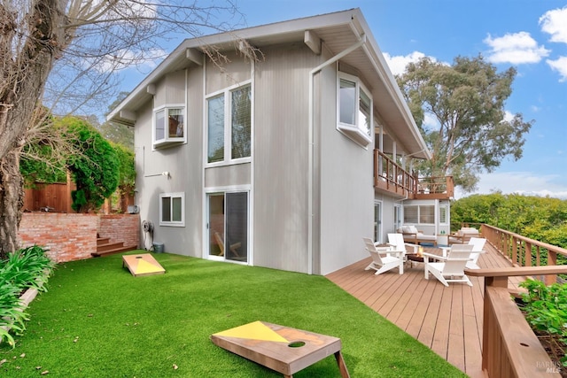 rear view of property featuring a yard, a wooden deck, and fence