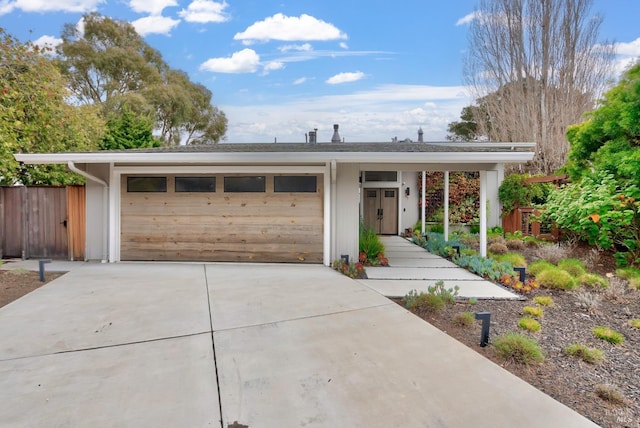 single story home with driveway, an attached garage, and fence