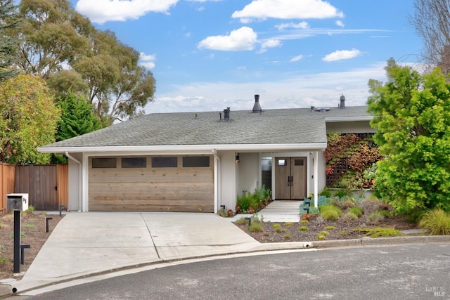 single story home featuring driveway, a shingled roof, a garage, and fence