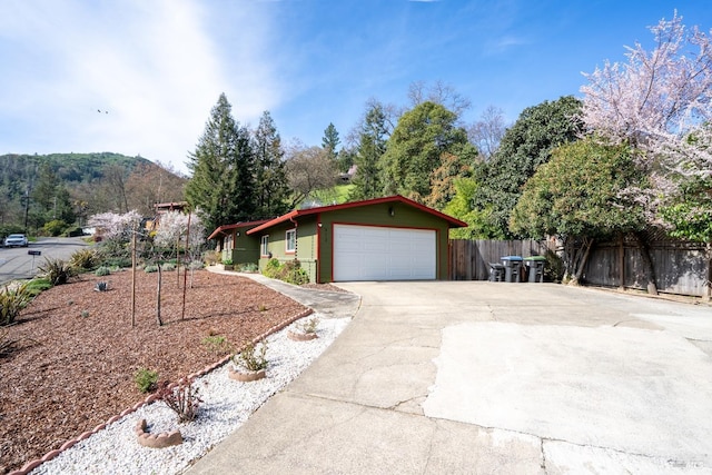 single story home with an attached garage, concrete driveway, and fence