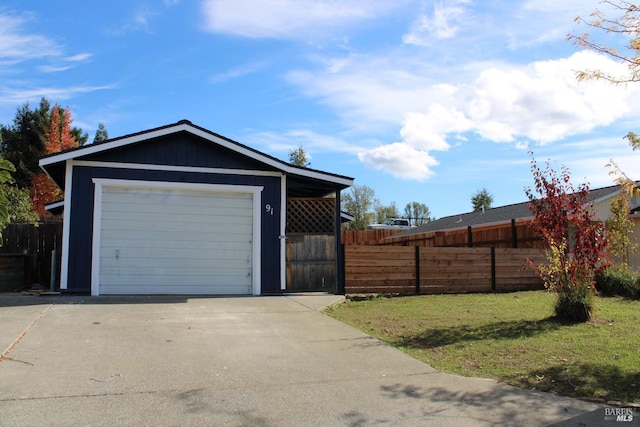 detached garage featuring driveway and fence