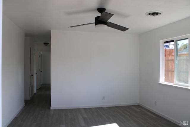 empty room featuring a ceiling fan, visible vents, baseboards, and wood finished floors