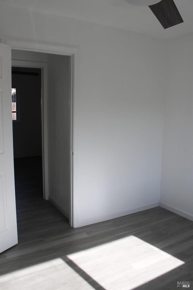 spare room with baseboards and wood finished floors