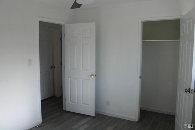 unfurnished bedroom with a closet, wood finished floors, a walk in closet, and baseboards