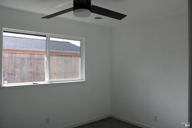 empty room featuring baseboards, visible vents, dark wood finished floors, and a ceiling fan