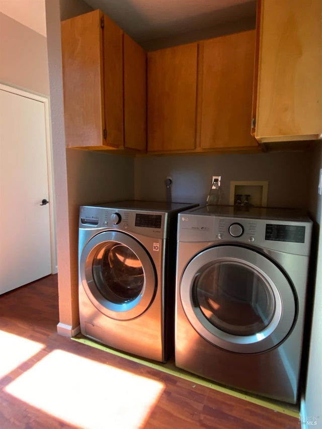 clothes washing area with cabinet space, wood finished floors, and independent washer and dryer