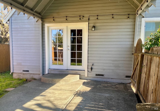 view of exterior entry with crawl space, fence, and french doors