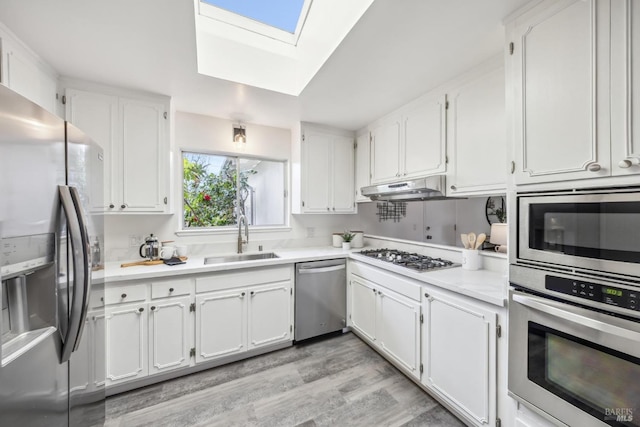 kitchen with appliances with stainless steel finishes, white cabinetry, a sink, and under cabinet range hood