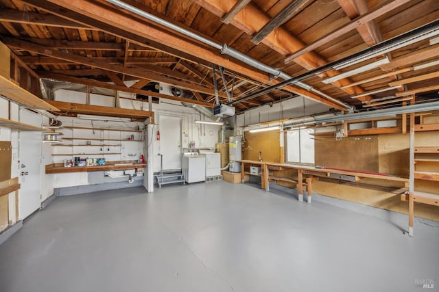 garage featuring secured water heater, separate washer and dryer, and a workshop area