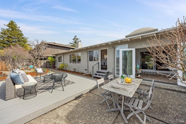 back of property with stucco siding, outdoor dining space, fence, a deck, and an outdoor living space