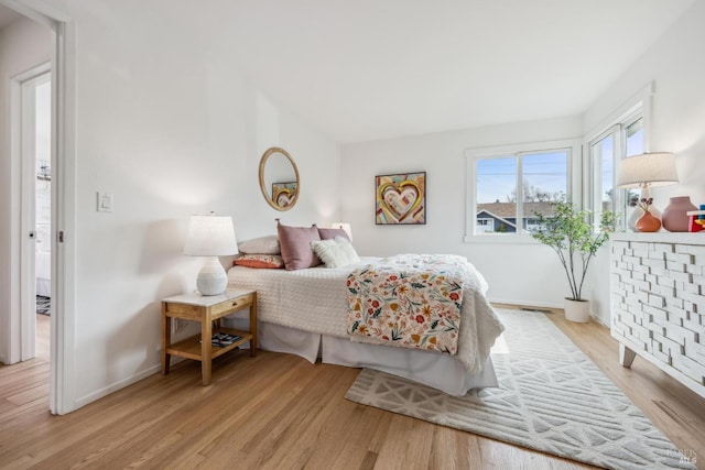 bedroom featuring light wood finished floors and baseboards