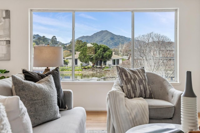 sitting room featuring a water and mountain view, baseboards, and wood finished floors