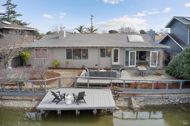 rear view of property with a chimney, fence, an outdoor living space, and stucco siding