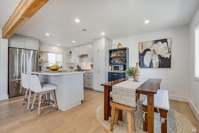 kitchen with visible vents, appliances with stainless steel finishes, light wood-type flooring, open shelves, and a kitchen bar