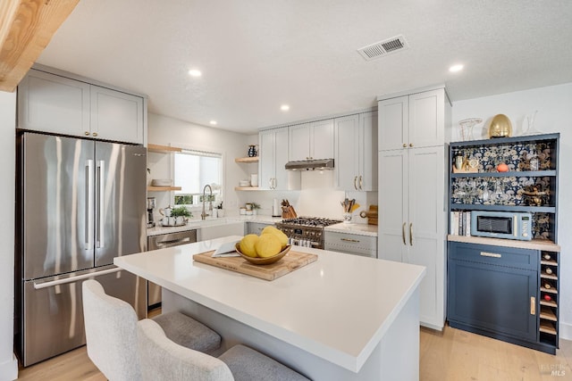 kitchen featuring open shelves, visible vents, appliances with stainless steel finishes, a sink, and under cabinet range hood