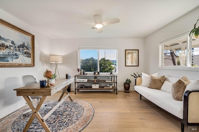 office featuring ceiling fan, plenty of natural light, baseboards, and light wood-style floors