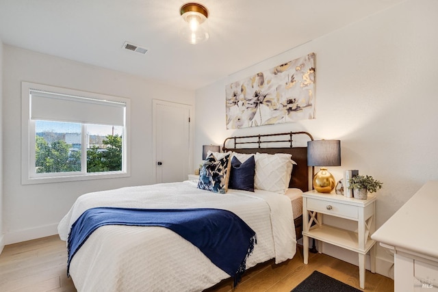 bedroom featuring baseboards, visible vents, and wood finished floors