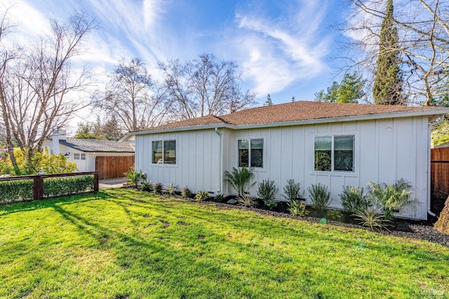 exterior space featuring fence, a front lawn, and board and batten siding