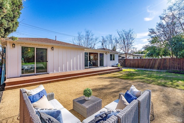 rear view of property featuring fence, an outdoor living space, and a wooden deck