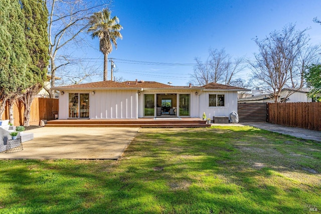 rear view of property featuring a deck, a yard, a patio area, and fence