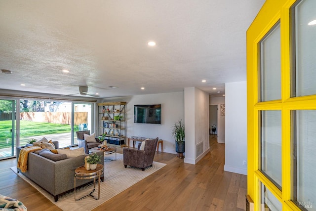 living room with a textured ceiling, wood finished floors, and recessed lighting