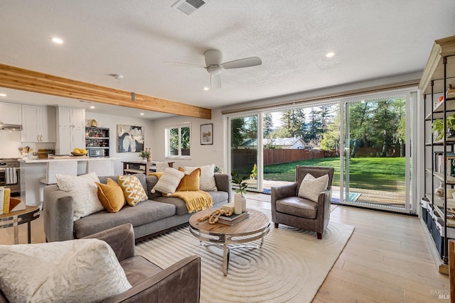 living room featuring a textured ceiling, light wood-style flooring, recessed lighting, a ceiling fan, and visible vents