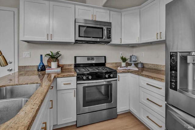 kitchen with stainless steel appliances, light wood-type flooring, and white cabinetry