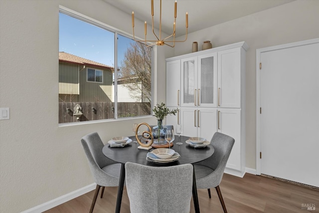 dining room with a chandelier, wood finished floors, and baseboards