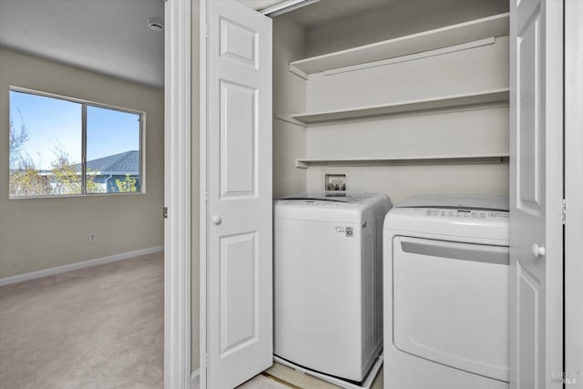 clothes washing area featuring baseboards, washing machine and dryer, light colored carpet, and laundry area