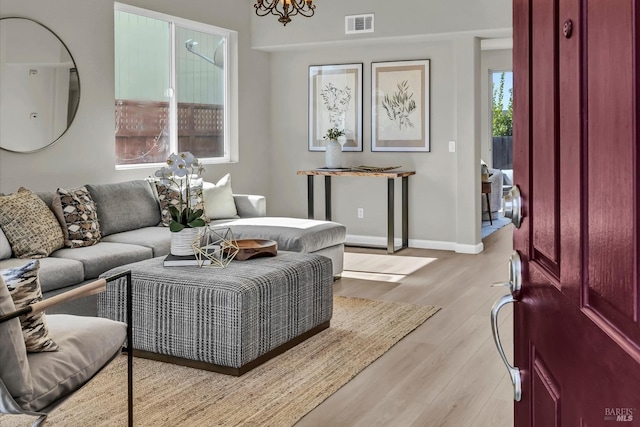 living area featuring baseboards, visible vents, a chandelier, and light wood-type flooring