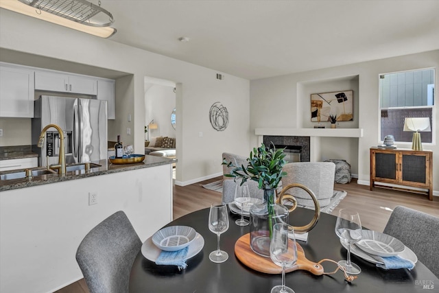 dining area with baseboards, wood finished floors, and a high end fireplace