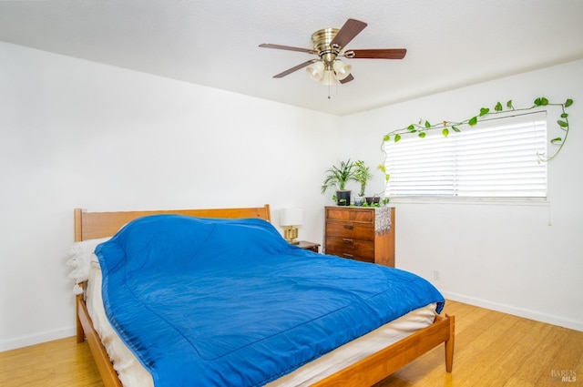 bedroom with ceiling fan, baseboards, and wood finished floors