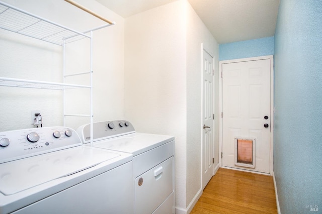 clothes washing area featuring baseboards, laundry area, light wood-type flooring, and washer and dryer