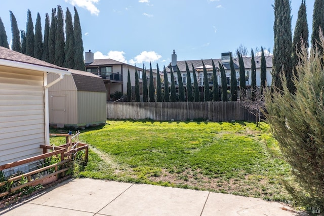 view of yard featuring fence, an outdoor structure, and a storage unit