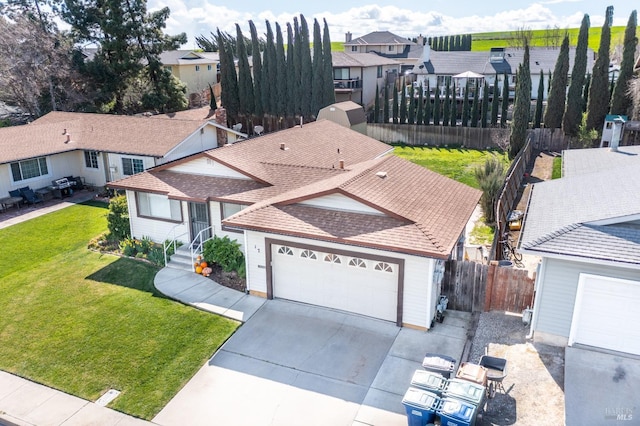 view of front of home featuring a garage, concrete driveway, a residential view, fence, and a front lawn